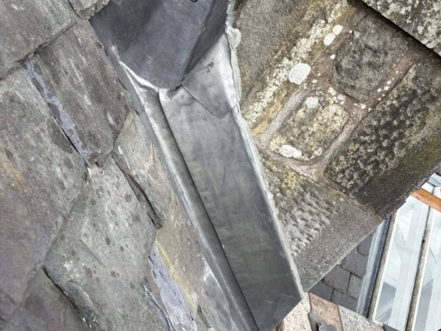 Lead work fitted between slate and stonework.