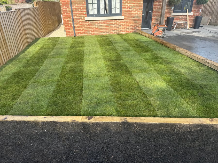 Freshly laid striped turf lawn with sleeper edge and patio.