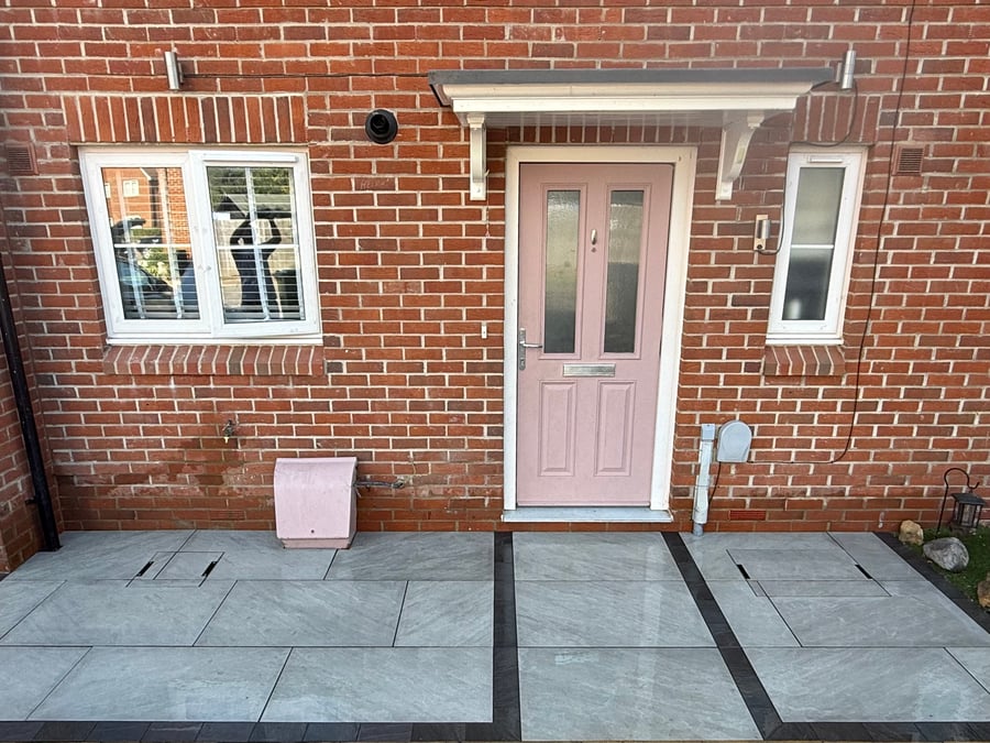 Grey paving with contrasting dark border by the front door.